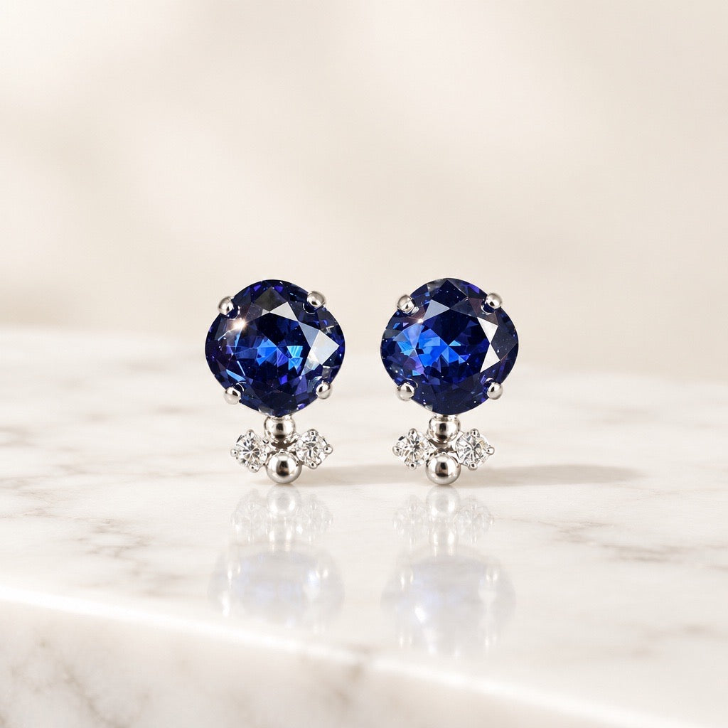 DAMICE Jewelry blauwe Swarovski oorsteker met ronde saffierblauwe kristal en zilveren accenten op marmeren ondergrond